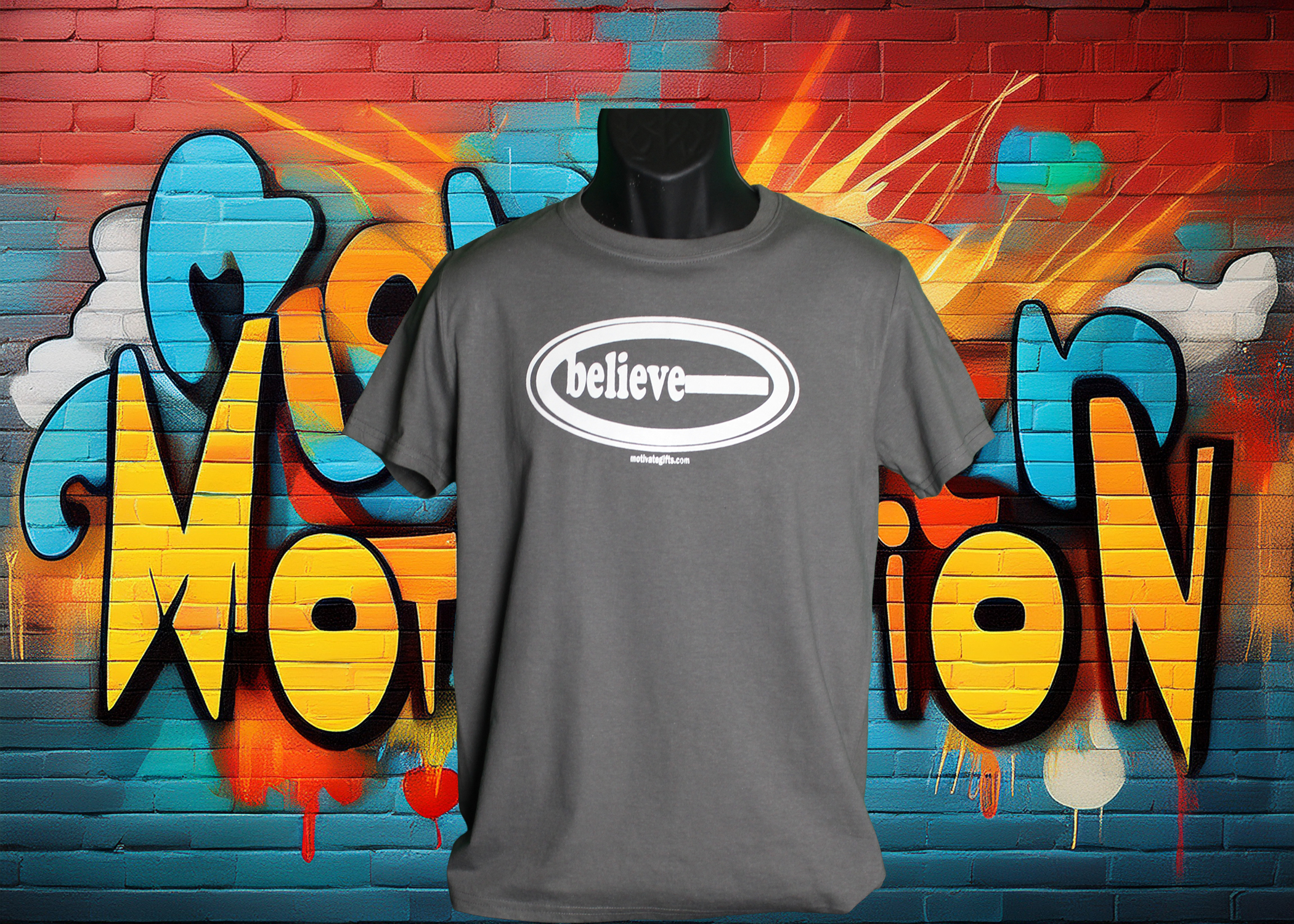 Gray T Shirt with the word Believe written on the front in White ink. With the words motivategifts.com written below image centered